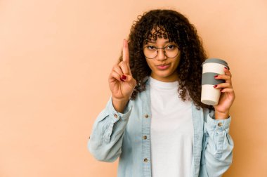 Genç Afro-Amerikan Afro kadın elinde hazır kahveyle bir numarayı parmaklarıyla gösteriyor..