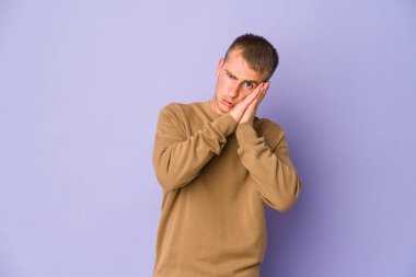 Beyaz tenli yakışıklı adam esniyor. Ağzı eliyle kapatan yorgun bir jest yapıyor..