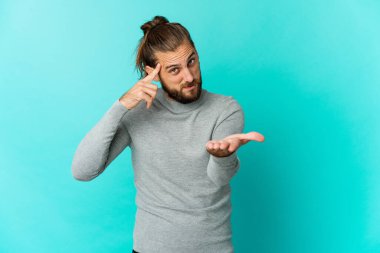 Uzun saçlı genç adam elinde bir ürünü tutuyor ve gösteriyor..