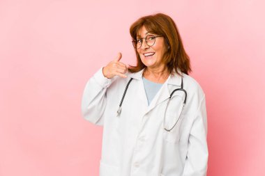 Orta yaşlı beyaz kadın izole edilmiş, parmaklarıyla bir cep telefonu hareketi gösteriyor..