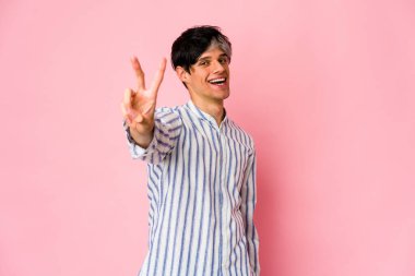 Genç, sıska, neşeli ve kaygısız İspanyol adam parmaklarıyla barış sembolü gösteriyor..