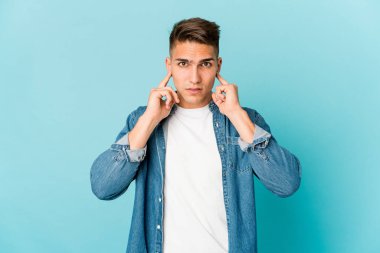 Genç beyaz yakışıklı adam kulaklarını parmaklarıyla kapatıyor, gürültülü bir ortam yüzünden stresli ve çaresiz..