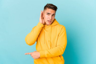 Beyaz tenli yakışıklı bir adam bir dedikoduyu dinlemeye çalışıyor..