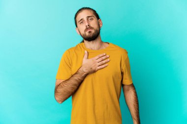 Uzun saçlı genç adam yemin ediyor, elini göğsüne koyuyor..