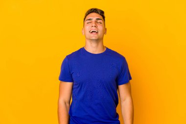 Genç, yakışıklı, beyaz bir adam izole edilmiş, rahat ve mutlu bir şekilde gülüyor, boynunda dişlerini gösteriyor..