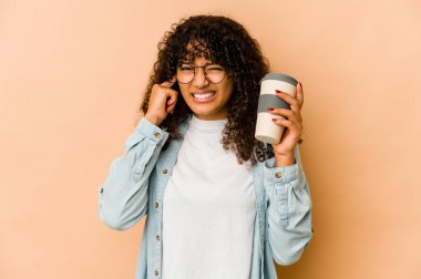 Genç Afro-Amerikan Afro kadın elinde kahve ile kulaklarını elleriyle kapatıyor..