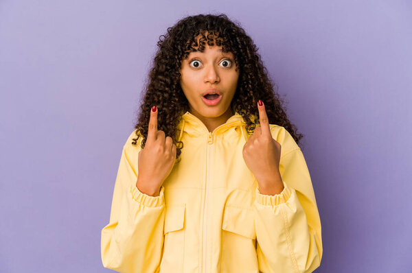 Молодая африканская американка афро-женщина изолирована, указывая вверх ногами с открытым ртом.