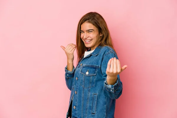 Young skinny caucasian teenager girl pointing with finger at you as if inviting come closer.