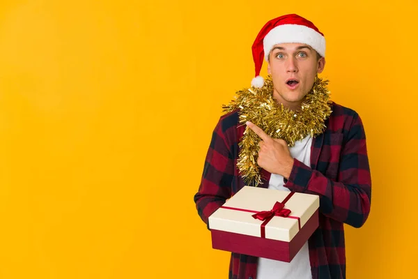 Jovem Caucasiano Com Chapéu Natal Segurando Presente Isolado Fundo Amarelo — Fotografia de Stock