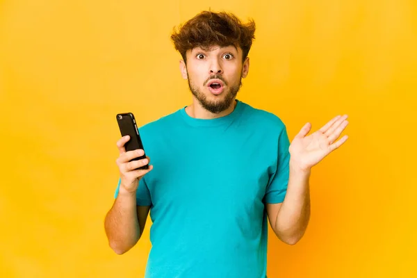 Young Indian Man Holding Phone Surprised Shocked — Stock Photo, Image