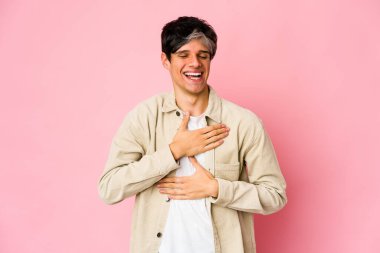 Genç, sıska İspanyol adam mutlu bir şekilde gülüyor ve ellerini karnının üstünde tutarak eğleniyor..