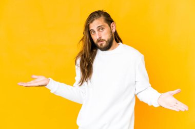 Uzun saçlı genç adam kafası karışmış görünüyor ve bir kopya alanı tutmak için omuz silkiyor..