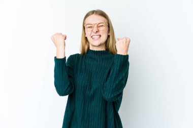 Beyaz arka planda yalnız yaşayan genç sarışın kadın tasasız ve heyecanlı bir şekilde tezahürat yapıyor. Zafer konsepti.