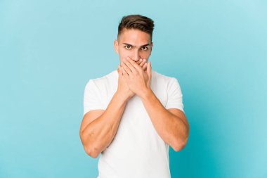 Genç, beyaz, yakışıklı bir adam izole edilmiş. Ağzını elleriyle kapatmış..