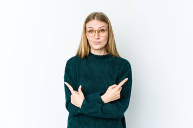 Beyaz arka planda izole edilmiş genç sarışın kadın iki seçenek arasında seçim yapmaya çalışıyor..