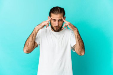 Uzun saçlı genç adam bir işe odaklanmış görünüyor, işaret parmaklarını işaret ediyor..