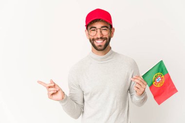 Genç İspanyol melez kadın elinde Portekiz bayrağı, gülümsüyor ve boş alanda bir şeyler gösteriyor..