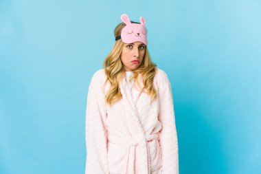 Genç sarışın beyaz kadın pijama giyiyor omuzlarını silkiyor ve gözleri açık..