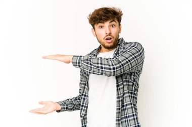 Beyaz arka plandaki genç Arap adam elleri arasında bir kopya alanı tutarken şok ve hayrete düştü..