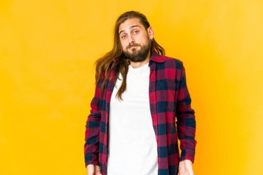 Uzun saçlı genç adam omuz silkiyor ve gözleri açık..