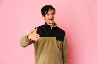 Genç, sıska İspanyol adam selamlaşmak için kameraya elini uzatıyor..