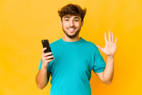 Jovem Indiano Segurando Telefone Sorrindo Alegre Mostrando Número Cinco Com — Fotografia de Stock