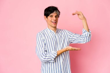 Genç, sıska İspanyol adam işaret parmaklarıyla küçük bir şey tutuyor, gülümsüyor ve kendinden emin..