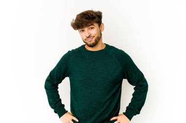 Beyaz arka plandaki genç Arap adam şaşkın, şüpheli ve güvensiz hissediyor..