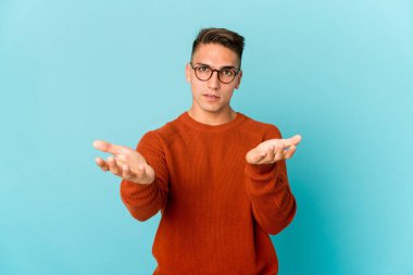 Kafkasyalı yakışıklı yalnız bir adam kollarıyla ölçek yapıyor, mutlu ve kendinden emin hissediyor..