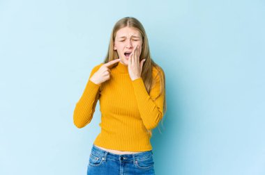 Mavi arka planda izole edilmiş genç sarışın kadın güçlü bir diş ağrısı, azı dişi ağrısı var..