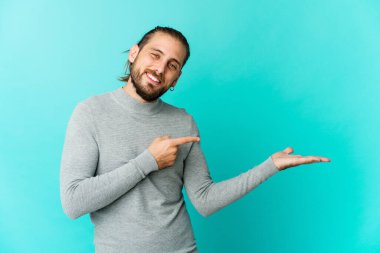 Uzun saçlı genç adam, elinde bir fotokopi odası tutarken heyecanlı görünüyor..