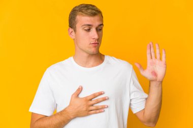 Beyaz tenli yakışıklı bir adam yemin ediyor, elini göğsüne koyuyor..