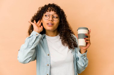 Genç Afro-Amerikan Afro kadın elinde hazır kahveyle bir dedikoduyu dinlemeye çalışıyor..