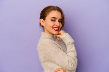 Genç Arap melez kadın gülümsüyor mutlu ve kendinden emin, elleriyle çenesine dokunuyor..