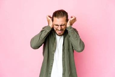 Uzun saçlı genç adam elleriyle kulaklarını kapatıyor..