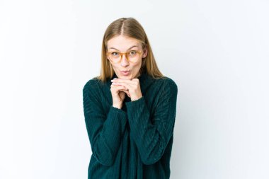 Beyaz arka planda izole edilmiş genç sarışın kadın şans için dua ediyor, şaşırmış ve ağzı açık bir şekilde önüne bakıyor..