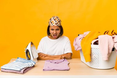Giysileri ütüleyen genç İspanyol kadın çok sinirli ve agresif çığlıklar atıyor..