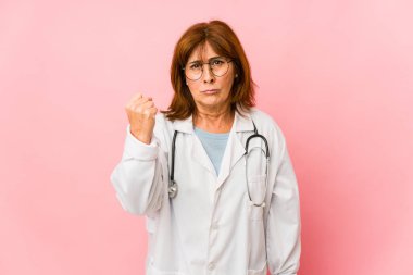Middle age caucasian doctor woman isolated showing fist to camera, aggressive facial expression.
