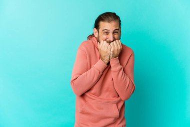 Uzun saçlı genç adam tırnak yiyor, gergin ve endişeli görünüyor..