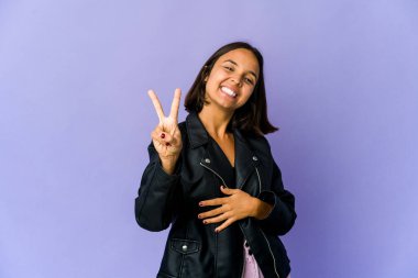 Genç melez kadın neşeli ve kaygısız parmaklarıyla barış sembolü gösteriyor..