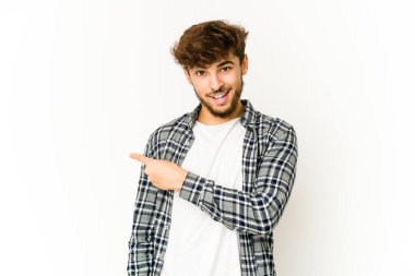 Beyaz arka plandaki genç Arap adam gülümsüyor ve boş alanda bir şeyler gösteriyor..