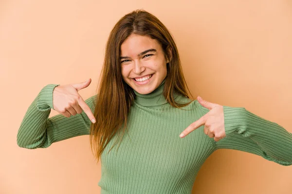 Young skinny caucasian teenager girl points down with fingers, positive feeling.