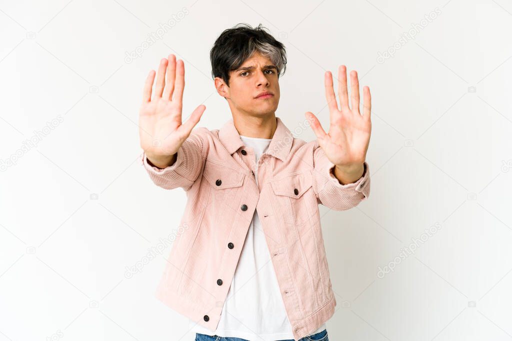Young skinny hispanic man standing with outstretched hand showing stop sign, preventing you.