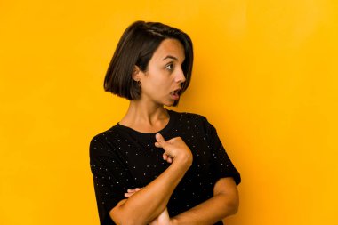 Sarı üzerine izole edilmiş genç İspanyol kadın parmağıyla işaret ederek şaşırdı, geniş bir gülümsemeyle..