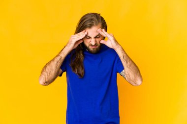 Uzun saçlı genç adam tapınaklara dokunuyor ve baş ağrısı çekiyor..