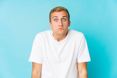 Genç beyaz yakışıklı adam omuz silker ve gözleri açık kalır..