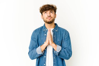 Beyaz arka plandaki genç Arap adam, el ele tutuşup, ağzının kenarında dua ediyor, kendinden emin..