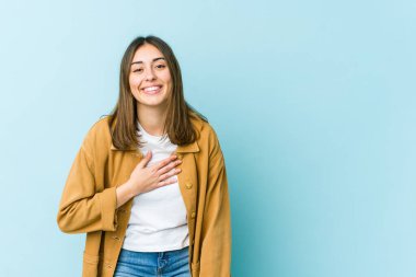 Genç beyaz kadın elini göğsüne koyup kahkahalarla gülüyor..