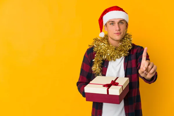 Junger Kaukasischer Mann Mit Weihnachtsmütze Hält Ein Geschenk Auf Gelbem — Stockfoto