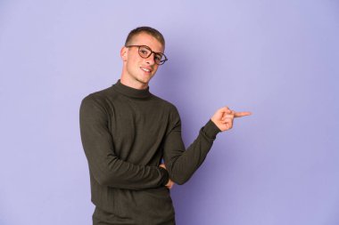 Genç, beyaz, yakışıklı adam işaret parmağıyla işaret ederek gülümsüyor..